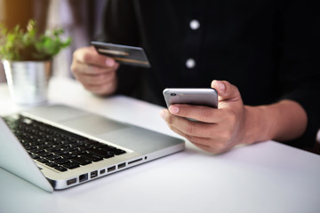 Male businessmen use credit cards to conduct financial transactions through phones, tablet, and laptop in the morning.