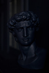 Fototapeta na wymiar Gypsum copy of ancient statue Apollo head in trend classic blue color. Plaster sculpture man face