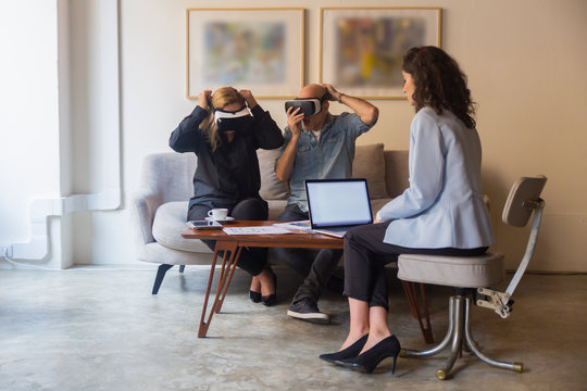 Excited mature people wearing VR glasses. Confident young woman introducing new product with help of virtual reality headsets. Technology concept - Powered by Adobe