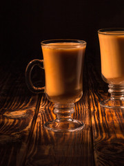 tea with milk in a glass mug on a black background. 