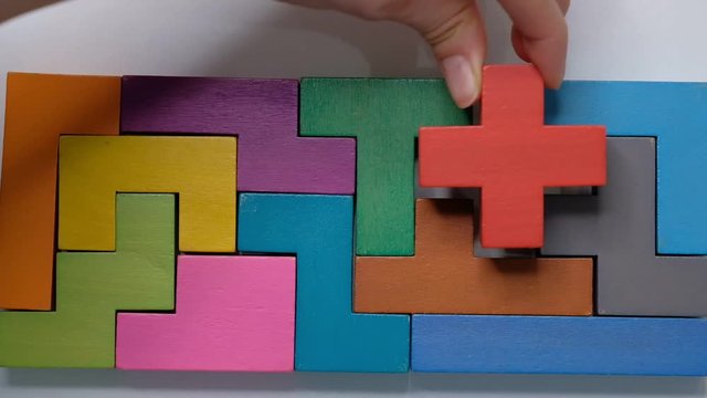 Closeup Slow motion. Hand holding piece of wooden block puzzle. wood cube stacking. Concept of complex and smart logical thinking.