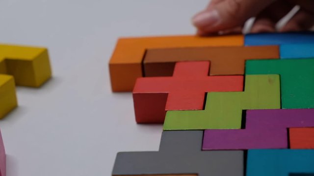 Closeup Slow motion. Hand holding piece of wooden block puzzle. wood cube stacking. Concept of complex and smart logical thinking.
