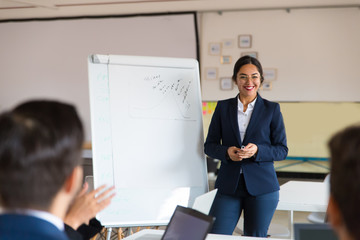 Smiling Asian business trainer working with employees. Group of workers sitting at table and...