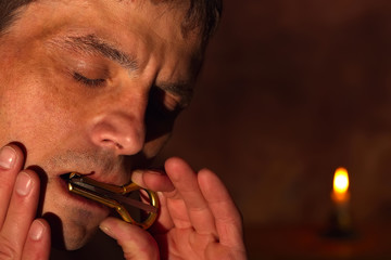 A man plays the harp. Colored lighting. Mysterious atmosphere. The room is in the twilight.