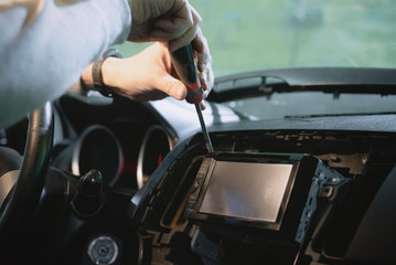 Auto electrician is installing a car radio sound system close up.