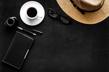 Blogger's work desk with hat and notebook on black background top-down copy space