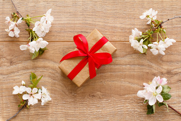 Gift box with cherry flowers on the wooden background.