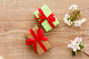 Gift boxes with cherry flowers on the wooden background.