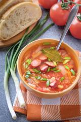 Tomato soup with smoked sausages, bread, green onion, tomatoes and kitchen towel