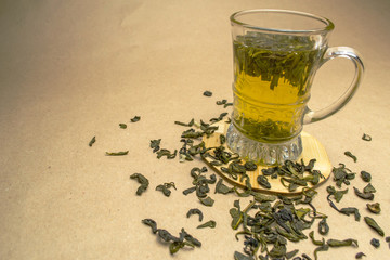 Glass cup of green tea on a stand with dried leaves of green tea