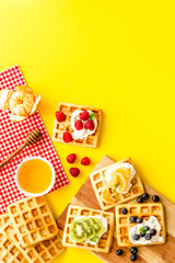Breakfast with freashly baked belgian waffles on yellow background top-down frame copy space
