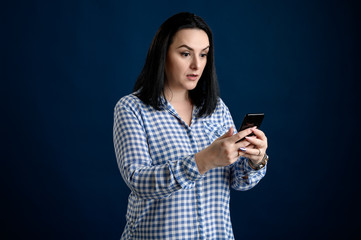 Beautiful woman dressed casually looks surprised at the phone