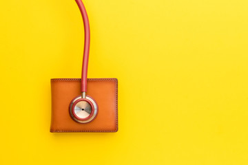 Doctor stethoscope and the new leather brown men wallet on yellow background. Budget for health check or money and financial concept