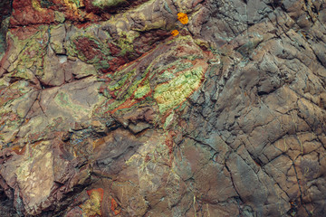 Image of mountain of layered rock close up. Brown green blue yellow colors rock formation.