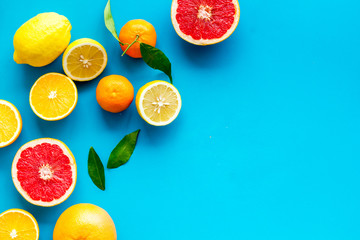 Citrus fruits frame - halfs of lemons, grapefruits, leaves - on blue background top-down copy space