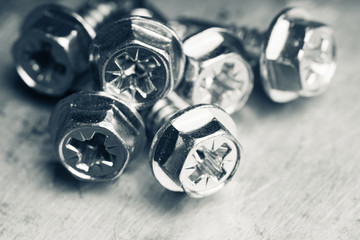 Tapping screw made of steel on the dark rustic background. Selective focus. Shallow depth of field....