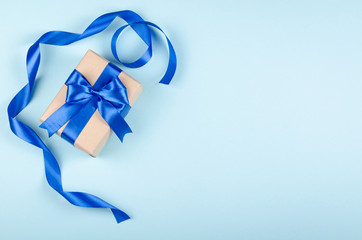 Gift box on blue background composition, present with ribbon and bow.