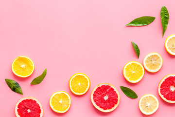 Citrus slices frame - lemons, grapefruits, leaves - on pink background top-down copy space