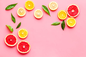 Citrus slices frame - lemons, grapefruits, leaves - on pink background top-down copy space