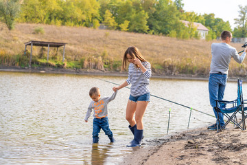 Mom with a small son walks along the sandy shore of the lake in rubber boots. Hanging out with...