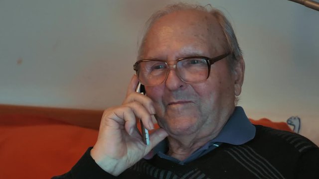 Alter Mann mit Hornbrille telefoniert mit Klapphandy