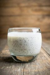 Plain yogurt with chia seeds in glass on the rustic wooden background. Selective focus.