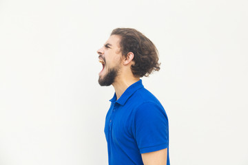 Side view of angry young man screaming. Angry man screaming loud with wide open mouth. Negative...