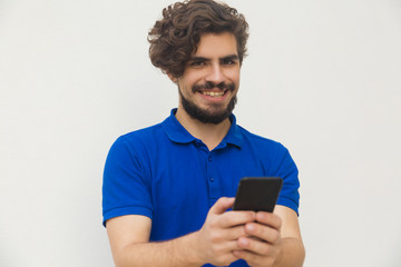 Front view of smiling bearded man holding phone . Cheerful guy using modern smartphone in hands. Technology and communication concept