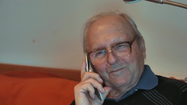 Alter Mann mit Hornbrille telefoniert mit Klapphandy