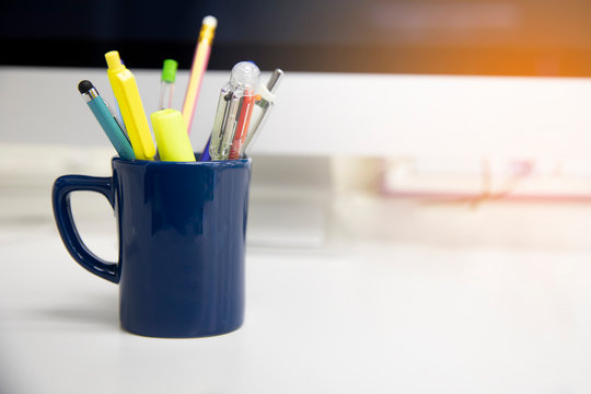 Pens And Pencils In Glass Cup On The Desk