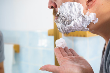 Guy shaving his beard in bathroom