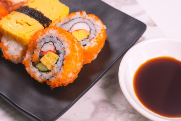 Sushi Roll with salmon, sushi maki roll and tamago sushi on black plate