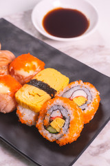 Sushi Roll with salmon, sushi maki roll and tamago sushi on black plate