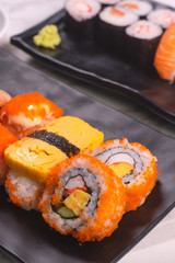 Sushi Roll with salmon, sushi maki roll and tamago sushi on black plate
