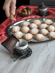 Preparation of delicious aromatic Turkish coffee with Cezve (Ibrik). Sweets and black coffee on a wooden table