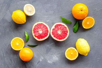 Fototapeta na wymiar Fresh citrus background. Oranges, grapefruits, leaves - whole fruits and halfs - on grey background top-down