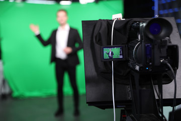 Presenter working in studio, focus on video camera screen