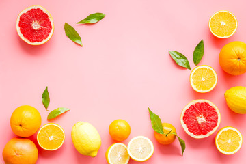 Fresh citrus frame. Oranges, tangerines, grapefruits, leaves on pink background top-down copy space