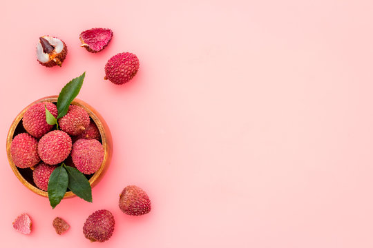 Fresh ripe lychee in bowl on pink desk top-down frame copy space