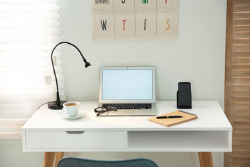 Stylish workplace with laptop, mobile phone and wireless charger