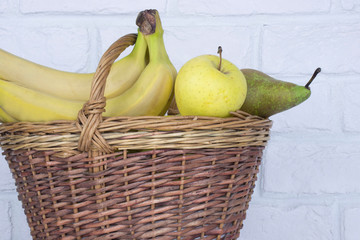 fresh colorful fruit in a basket against a brick wall