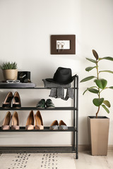 Obraz na płótnie Canvas Black shelving unit with shoes and different accessories near white wall in hall