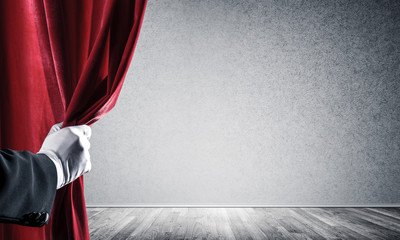 Concrete wall behind drapery curtain and hand opening it