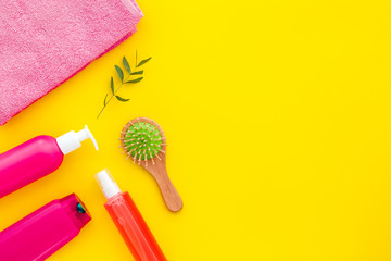 Hair care set with shampoo and towel - pink - on yellow background top-down frame copy space