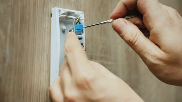 Electrician mounts infrared motion sensor for alarm system