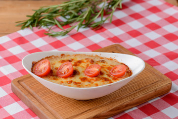 Piece of tomato lasagna in a white bowl. Dinner in a restaurant, cafe or diner. Healthy food, eating concept