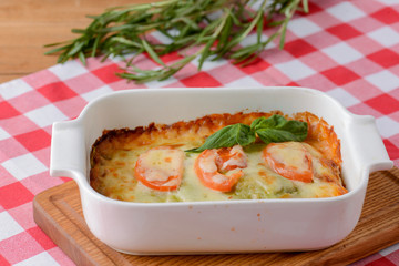 Piece of tomato lasagna in a white bowl. Dinner in a restaurant, cafe or diner. Healthy food, eating concept