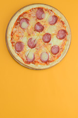 Flat lay pepperoni pizza isolated on bright yellow background. Pizza salami cut in slices. Fast food, junk food concept.