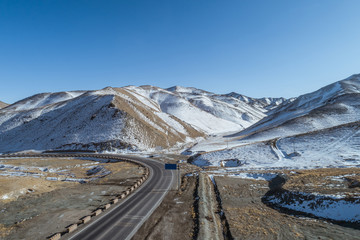 The country road winding through a valley surrounded by snowy mountains