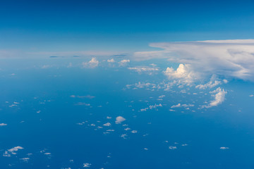 Naklejka na ściany i meble Aerial view of fluffy clouds through an airplane window